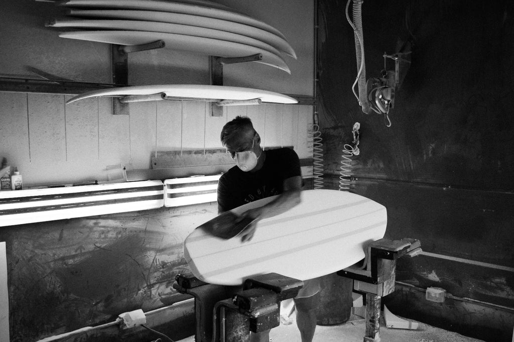Glenn Pang wearing a face mask and sanding one of his Majek Foilboards