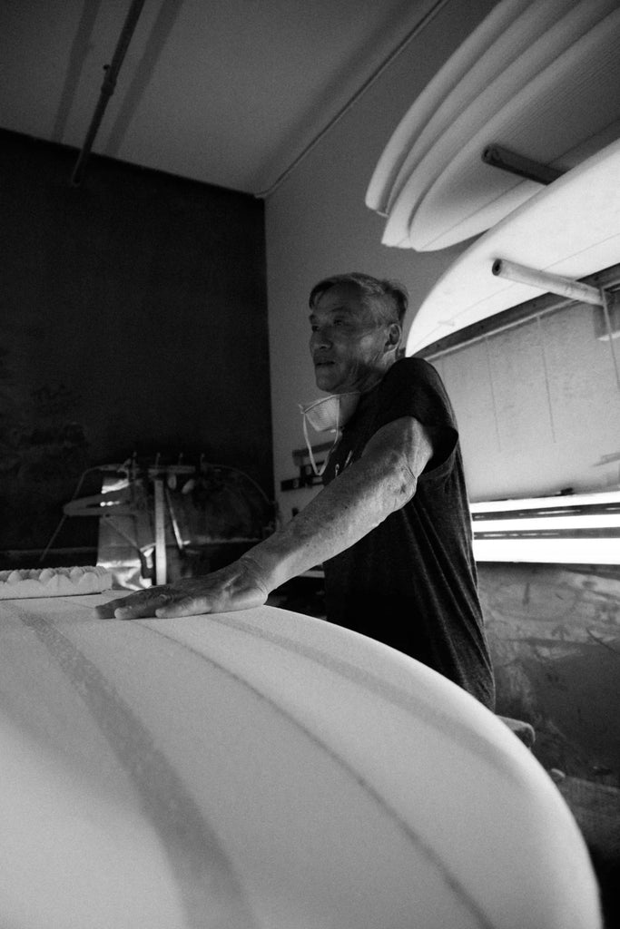 Glenn Pang discusses board design standing by one of his surfboard shapes in his workshop 