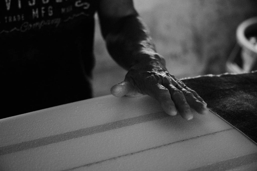 Close up shot of Glenn Pang's hand hovering one of his surfboard shapes in his Hawaii workshop