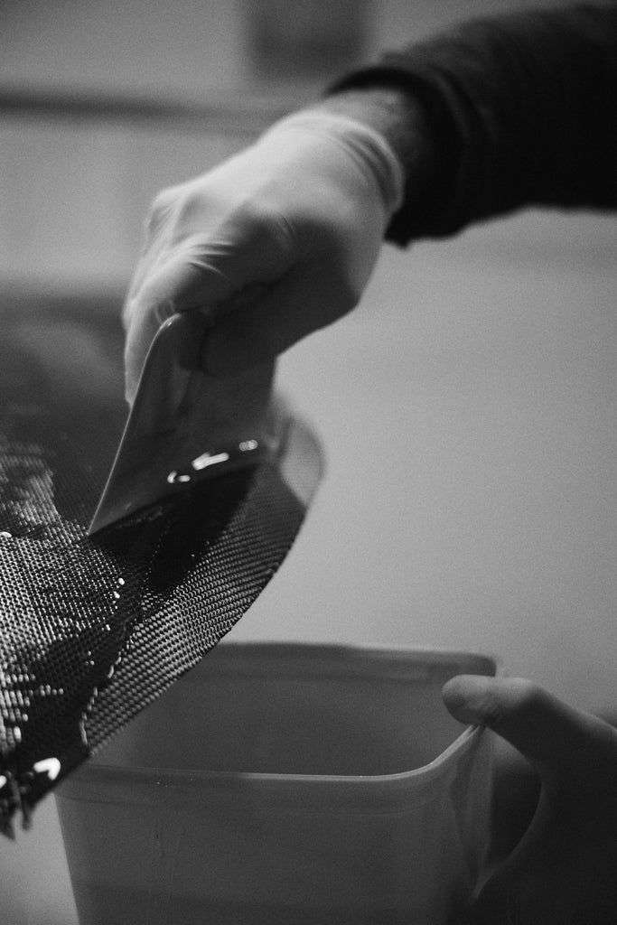 Mitch Hoakley's hand while glassing a carbon surfboard at Lucid Glassing Australia surfboard factory