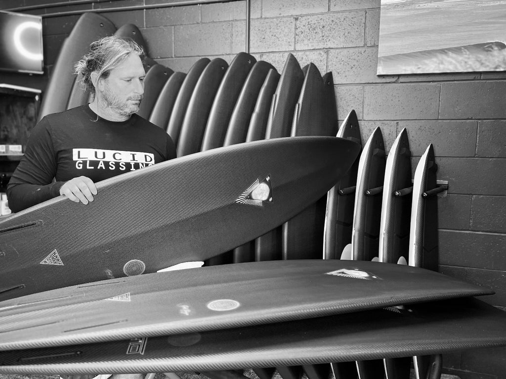 Amos Barriskill holding a Dark Arts carbon surfboard built at Lucid Glassing Australia surfboard factory